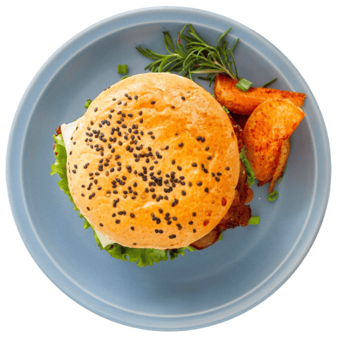 Boşqabda verilən burgerin yuxarıdan görünüşü, yanında kartof qızartması və təzə göyərti ilə.